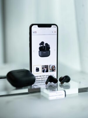 Close-up of a smartphone displaying wireless earbuds details, surrounded by sleek earbuds and a case.