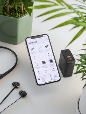 From above composition of modern mobile phone placed on working desk near uninterruptible power supply and wired earphones